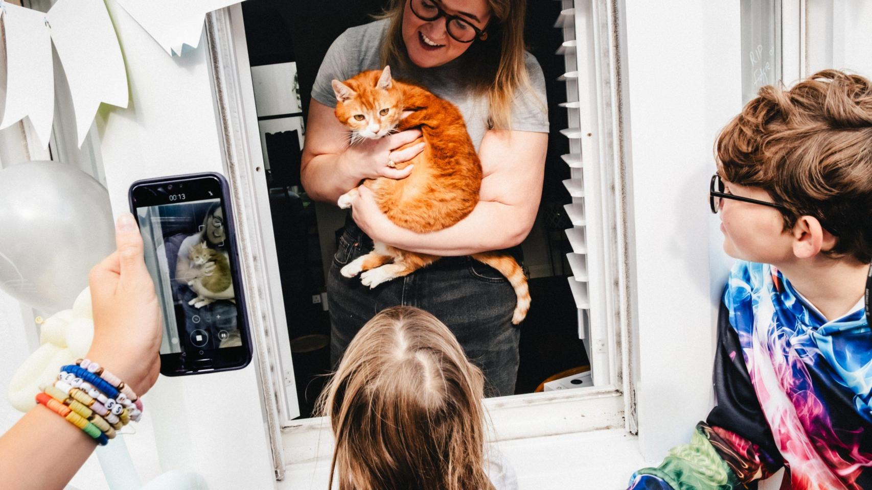 Una chica con un gato naranja en brazos.