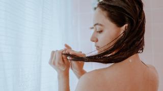 Una chica aplicándose productos en su melena.