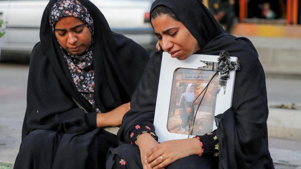 Two relatives hug the photograph of one of the girls who died in the attack.