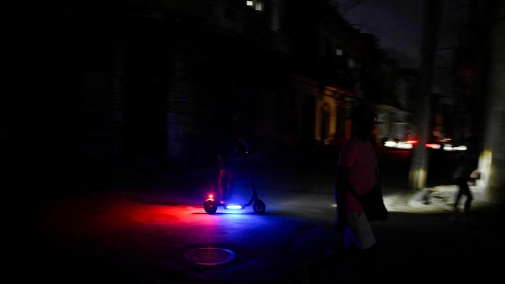 A person rides an electric scooter during a massive blackout that affects much of Cuba
