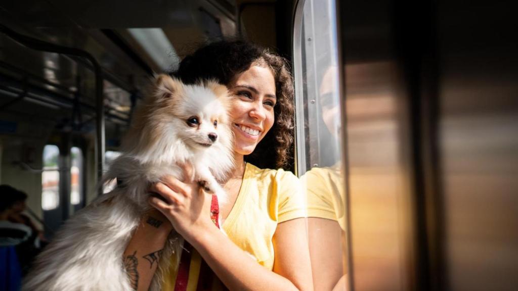 Une mujer con un perro en brazos en el metro.