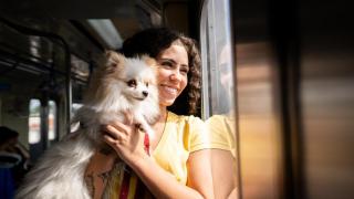 Une mujer con un perro en brazos en el metro.