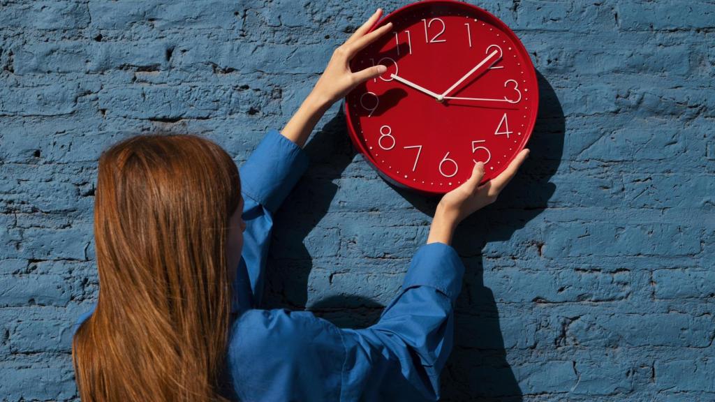 Mujer cambiando de hora un reloj.