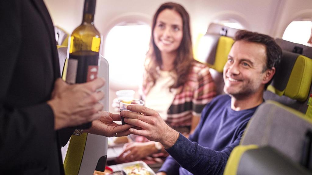 Una azafata de TAP sirviendo vinos a unos clientes.
