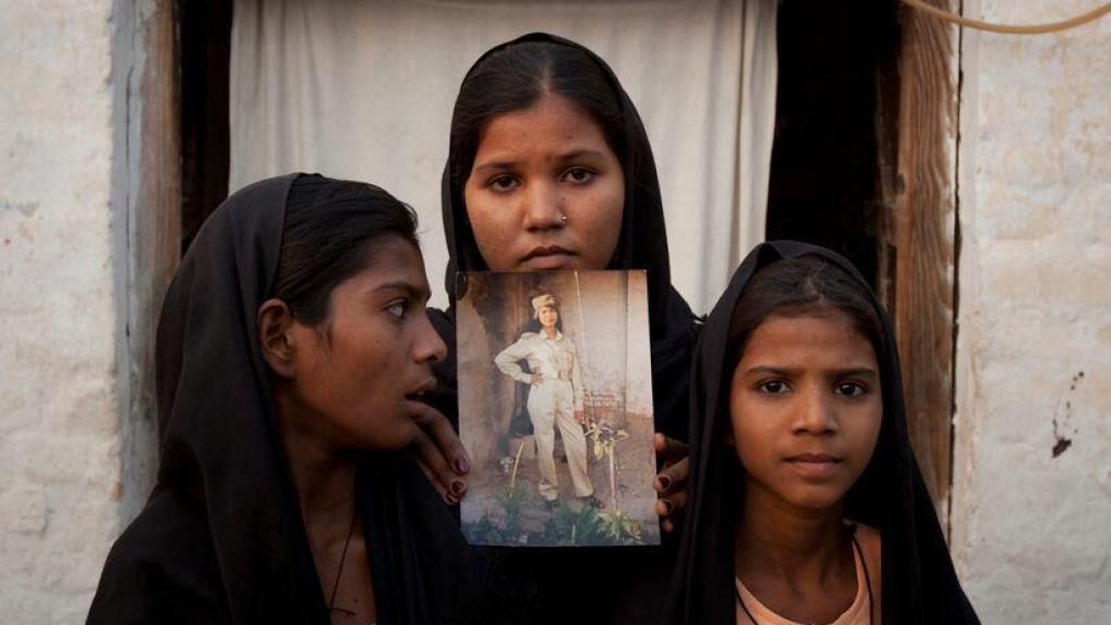 Tres hijas de Asia Bibi sostienen un retrato de su madre en 2010.