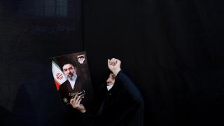 A woman holds an image of Mojtaba Khamenei at a march in Tehran.