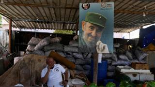 A thoughtful man sits near a photo of Fidel Castro.