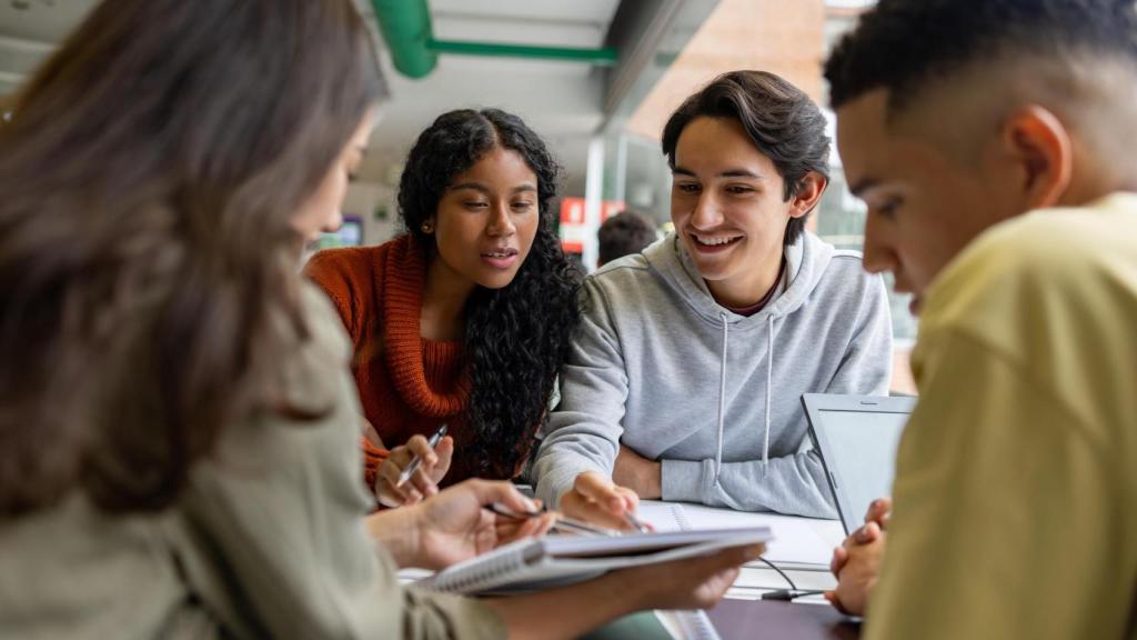 Cuatro estudiantes jóvenes en una biblioteca.