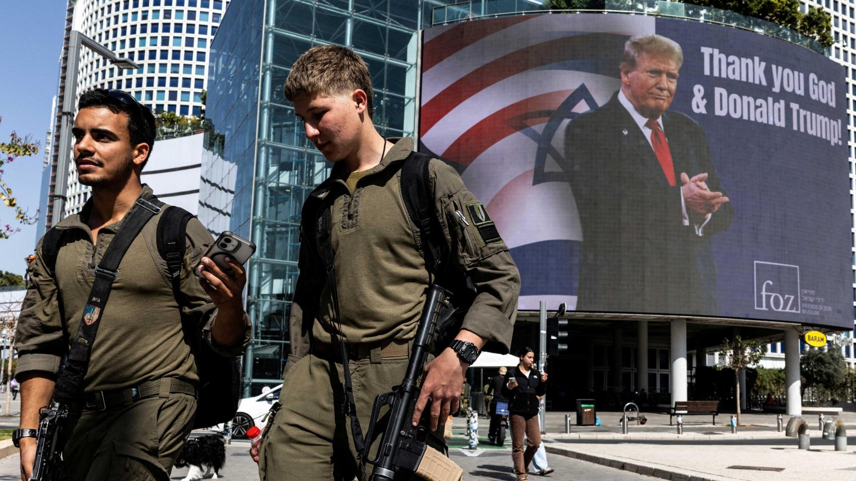 Soldados israelíes caminan junto a una valla publicitaria encargada por un grupo evangélico, que muestra una imagen de Donald Trump