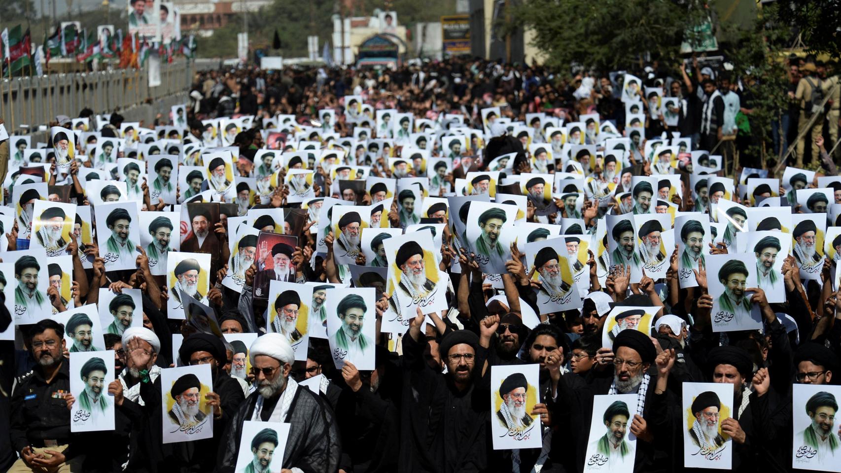 Musulmanes chiíes de Karachi sostienen carteles del nuevo líder supremo de Irán, Mojtaba Jamenei, junto al difunto líder supremo iraní, Alí Jamenei.