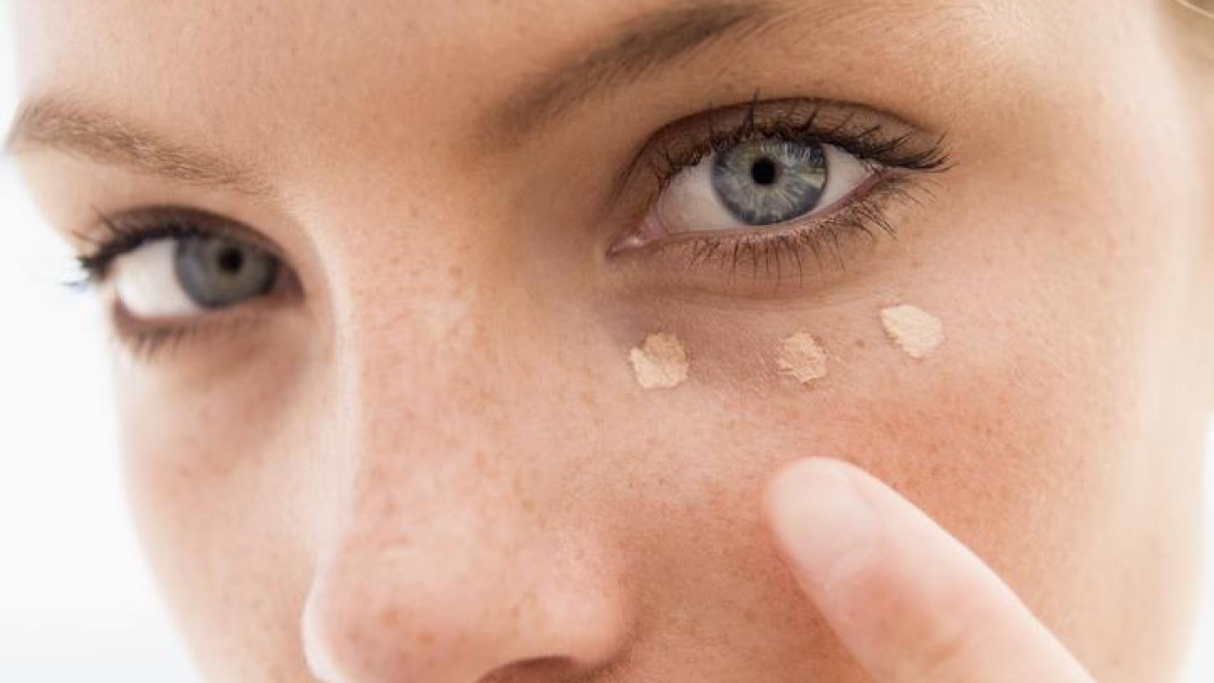 Mujer aplicándose corrector de ojera.
