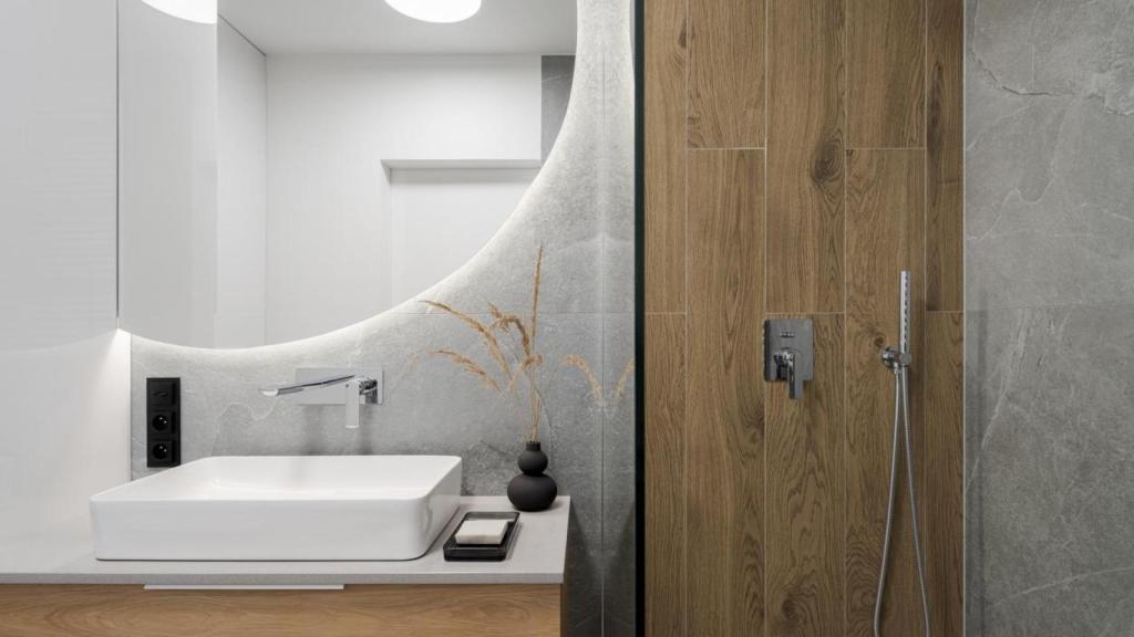 Baño moderno con detalles de madera y un espejo amplio.