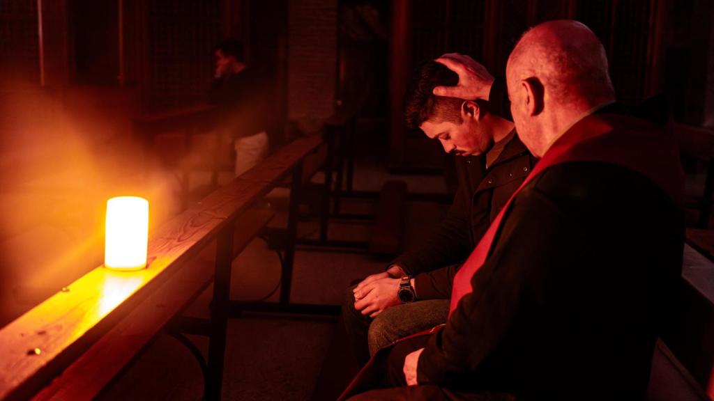 Otro de los sacerdotes presentes posa su mano sobre uno de los jóvenes durante las oraciones.