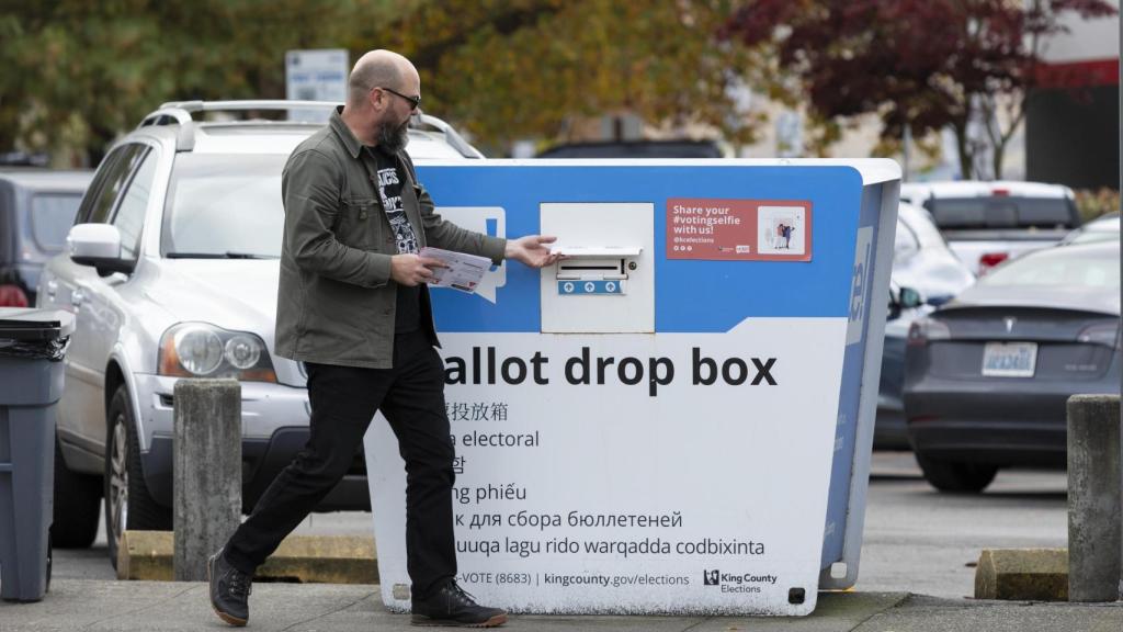 A voter places her ballot in a ballot drop box in Seattle in 2024.