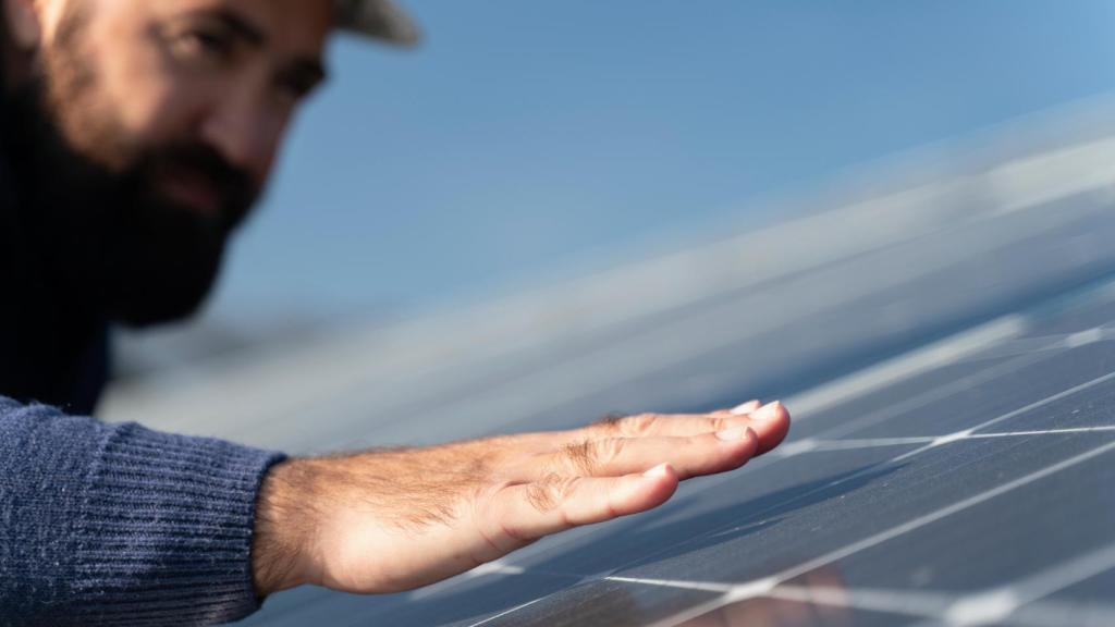 Un operario junto a un panel solar en un parque fotovoltaico.