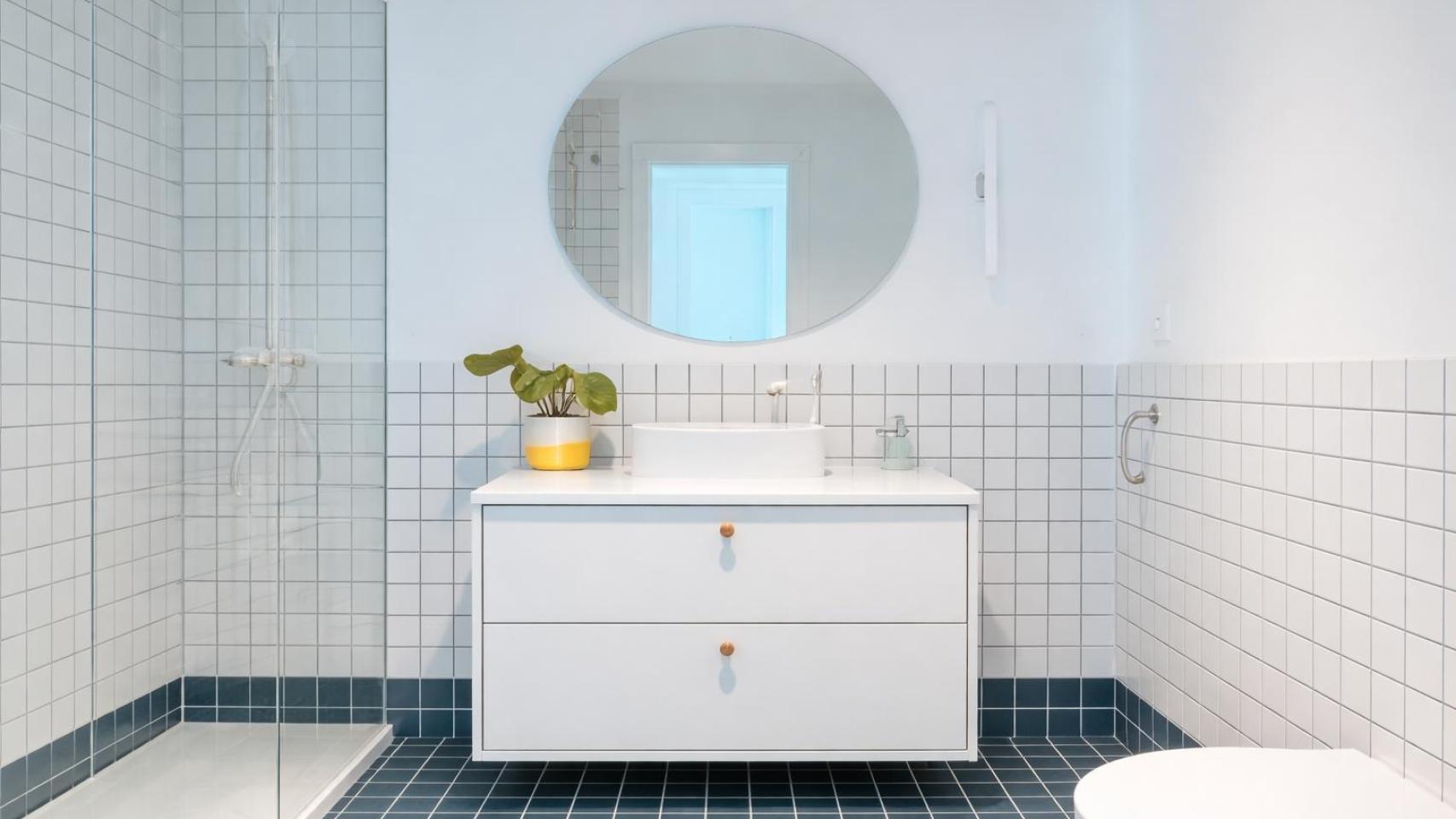 Baño de diseño con azulejo blanco y mueble suspendido en vivienda reformada.