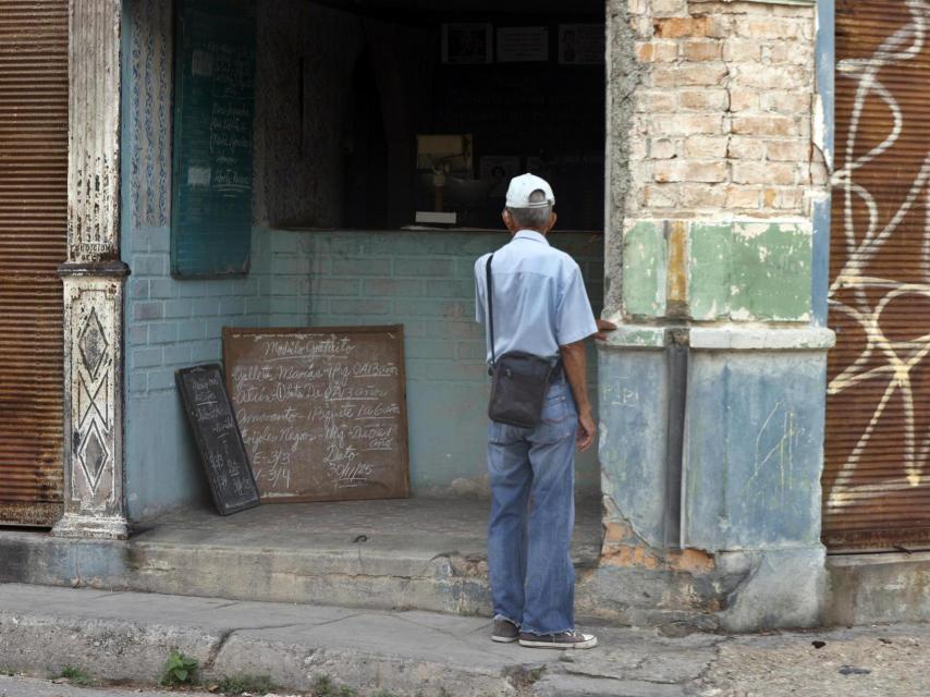 A Cuban man watches a list of products in a store in Havana, Cuba.
