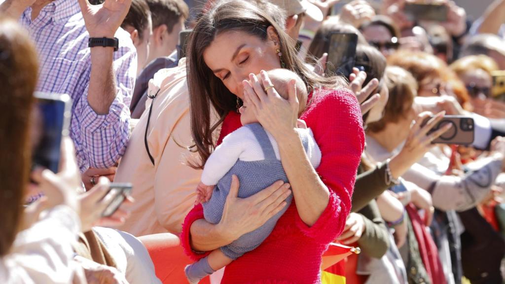 La Reina, a su llegada al Ayuntamiento de la ciudad posa con un bebé en brazos.