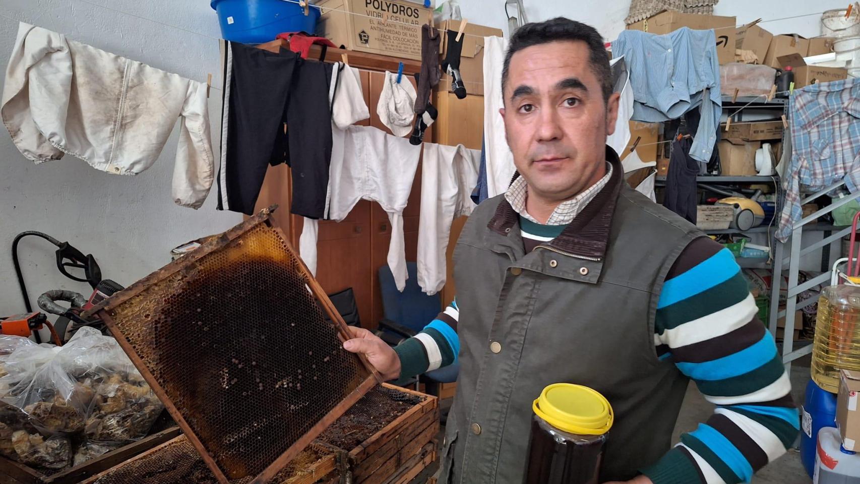 Rafael Canete, apicultor con una lámina de un panal en una mano y un tarro de miel en la otra.