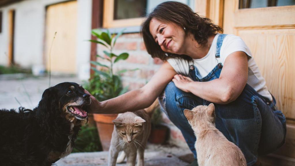 Una mujer con perro y gatos en su casa.