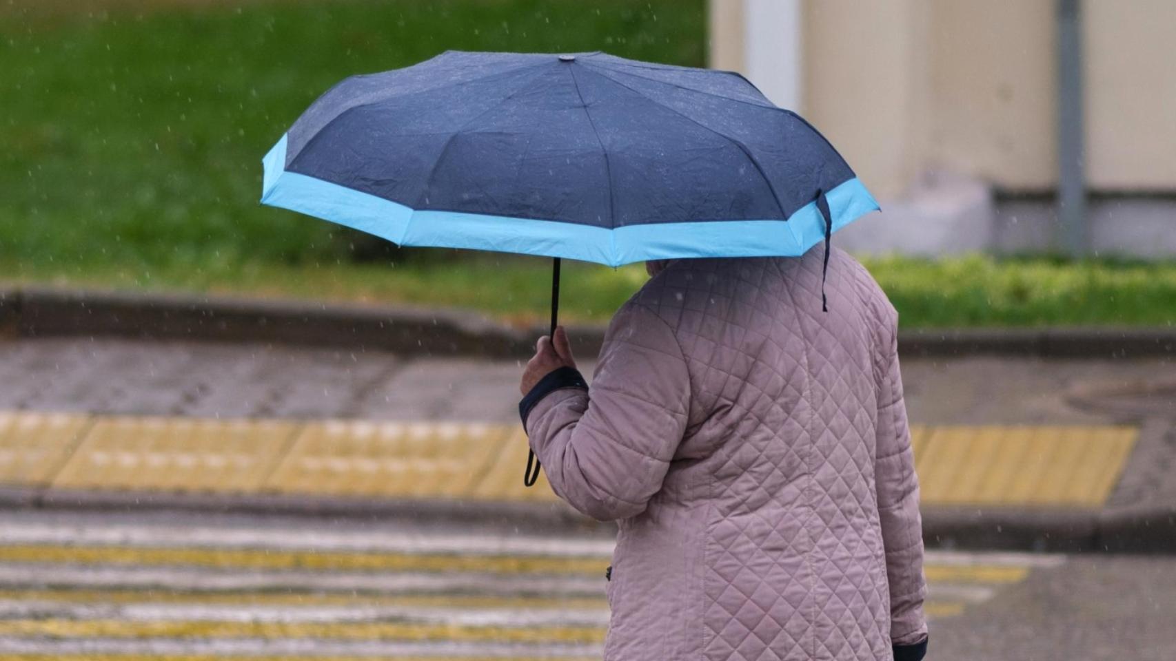 Una mujer pasea bajo la lluvia. 