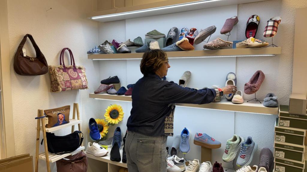 La propietaria de Calzados Nieves, Esperanza Díez, colocando una zapatilla en una estantería del establecimiento.