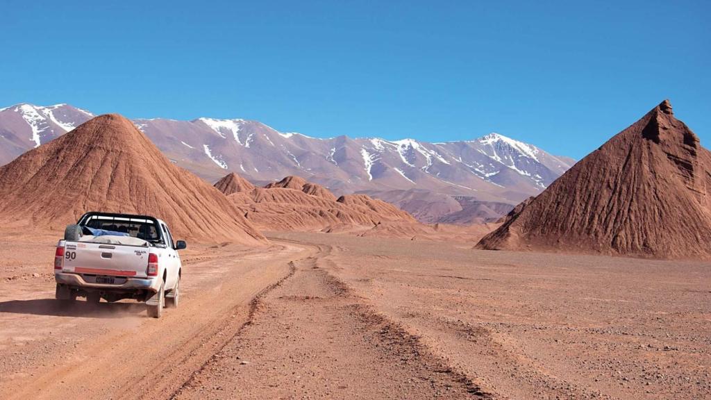Un coche conduciendo a través de las colinas rojas y las rocas de los Andes.