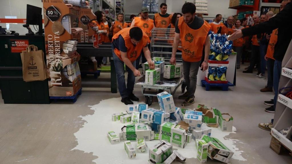 Varios miembros de Unións Agrarias derraman leche en el centro de Cash Galicia en protesta por la bajada del precio.