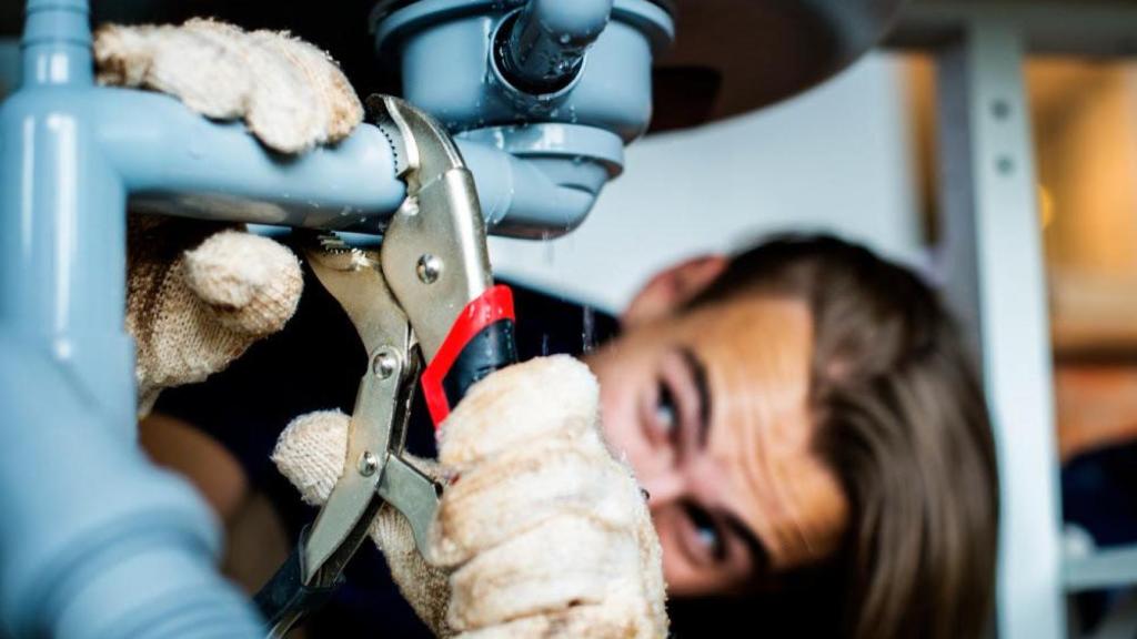 Un fontanero arreglando un tubería en una vivienda alquilada.