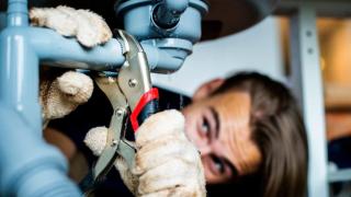 Un fontanero arreglando un tubería en una vivienda alquilada.