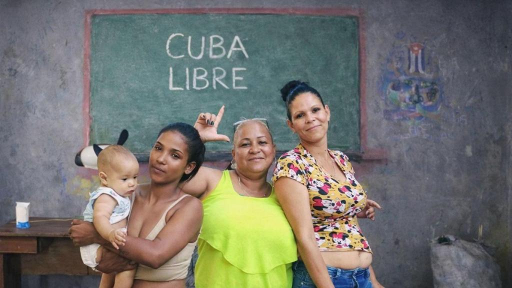 Yadira makes the sign of freedom surrounded by her daughters in her home in Las Tunas (Cuba).