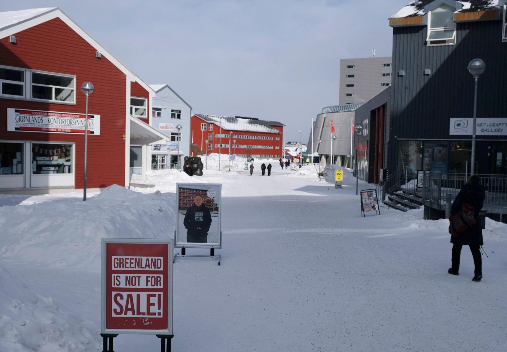Una persona pasa junto a un cartel electoral de un candidato a las próximas elecciones danesas, en Nuuk.
