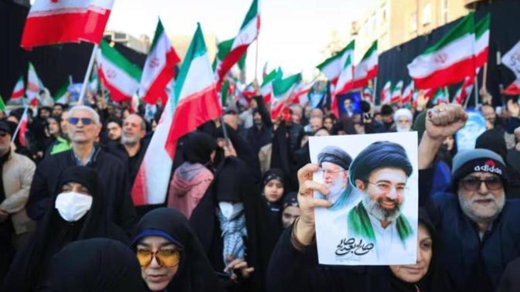 Manifestantes ondean banderas nacionales iraníes mientras se reúnen en una concentración en apoyo al nuevo Líder Supremo en la plaza Enghelab, en el centro de Teherán.