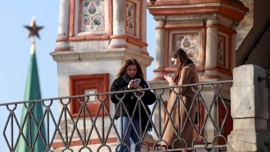Two women check their mobile phones in front of St. Basil's Cathedral in central Moscow.