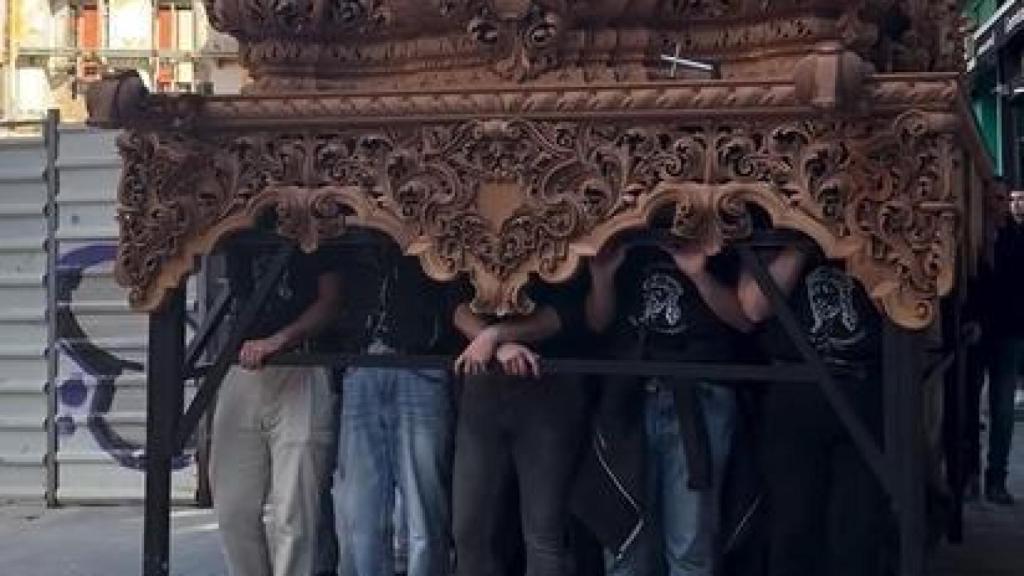 Los costaleros bajo el paso durante una sesión de preparación