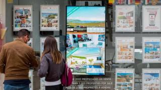 Dos personas ven carteles de vivienda en venta.