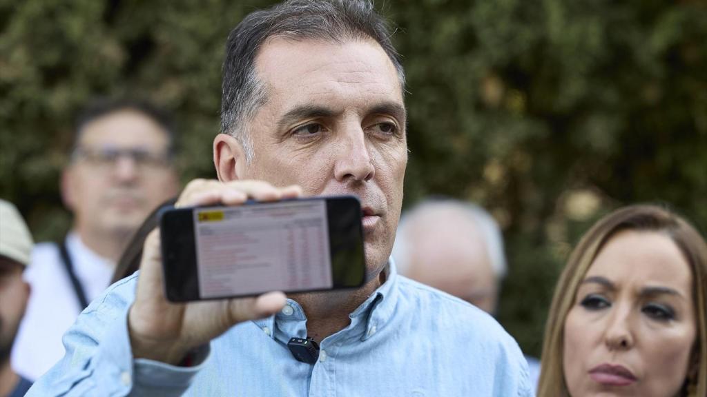 El policía nacional y portavoz de Vox de Inmigración, Seguridad e Interior, Samuel Vázquez, sostiene un móvil donde aparece el sistema estadístico de criminalidad.
