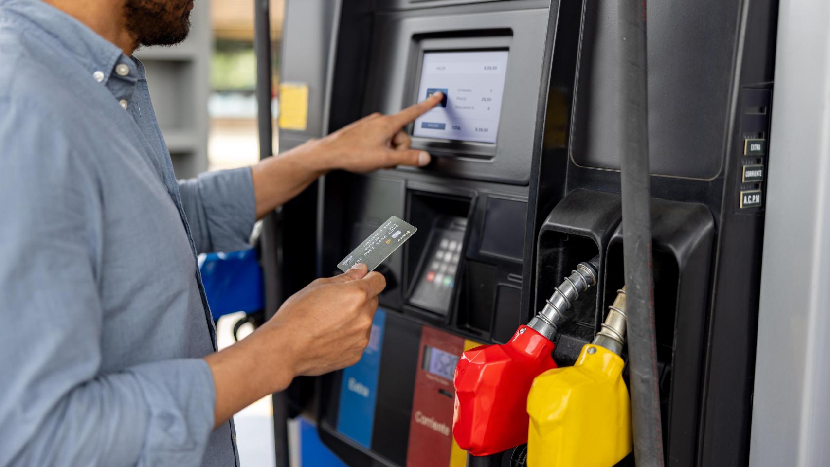 Hombre pagando con tarjeta en una gasolinera.