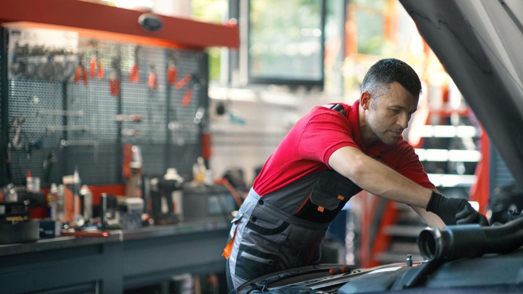 Mecánico de automóviles trabajando en el compartimento del motor.