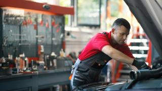 Mecánico de automóviles trabajando en el compartimento del motor.