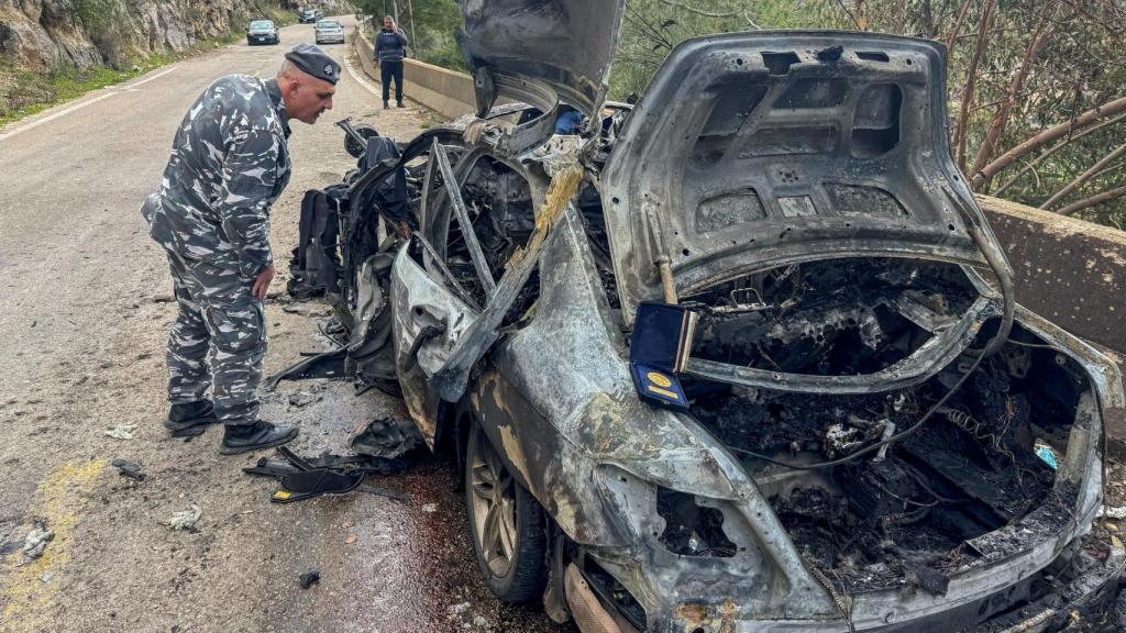 A police officer observes the destroyed car in which the Lebanese journalists were traveling