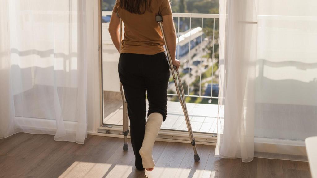 Imagen de ilustración de una mujer con la pierna escayolada.