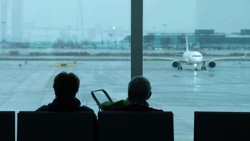 Imagen de dos pasajeros esperando su vuelo en un aeropuerto.