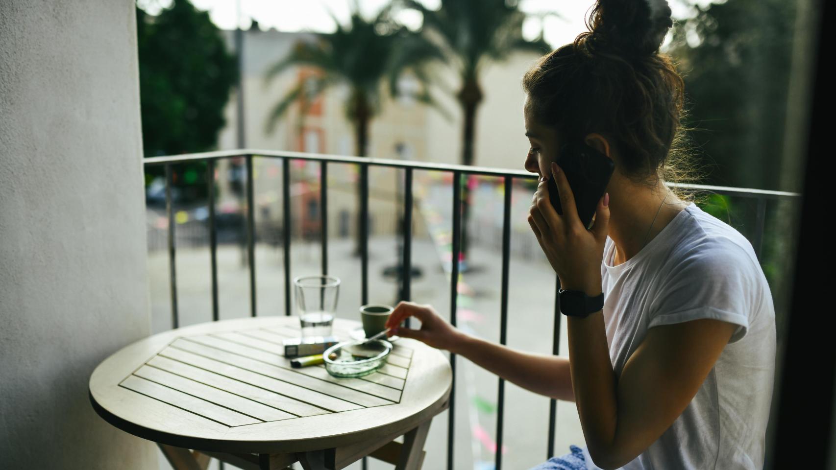Una mujer fumando en un balcón.