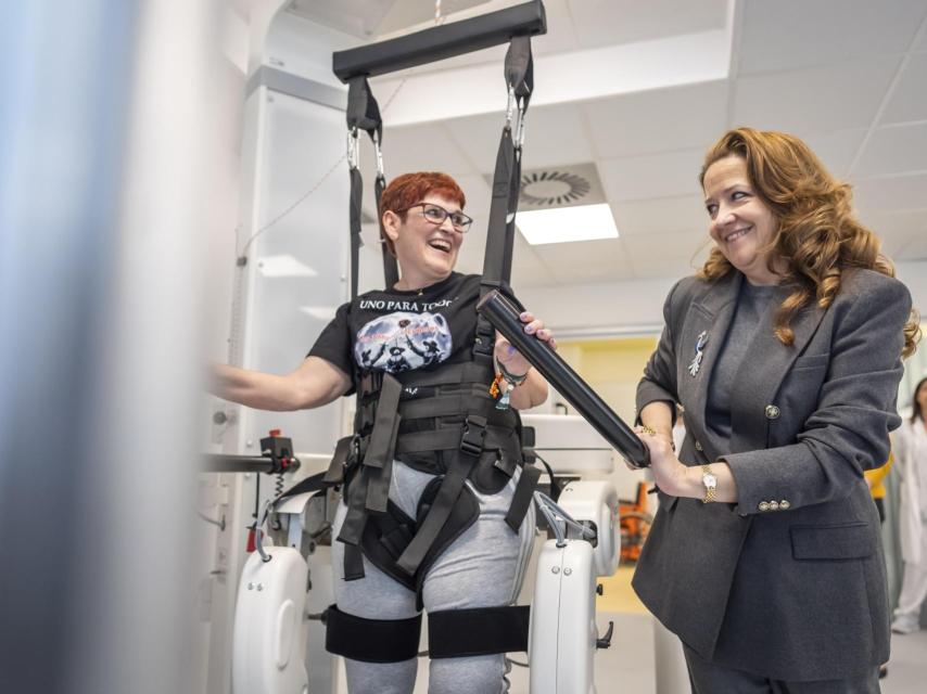Una paciente de ELA prueba el nuevo exoesqueleto en el Hospital Isabel Zendal junto a la consejera de Sanidad de la Comunidad de Madrid, Fátima Matute.