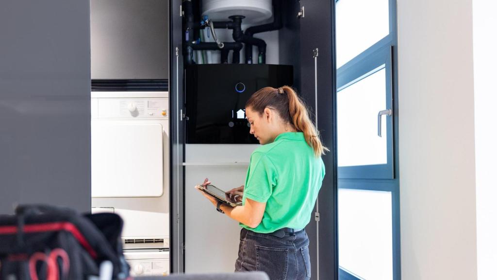 Una operaria trabaja en la instalación de aerotermia en una vivienda