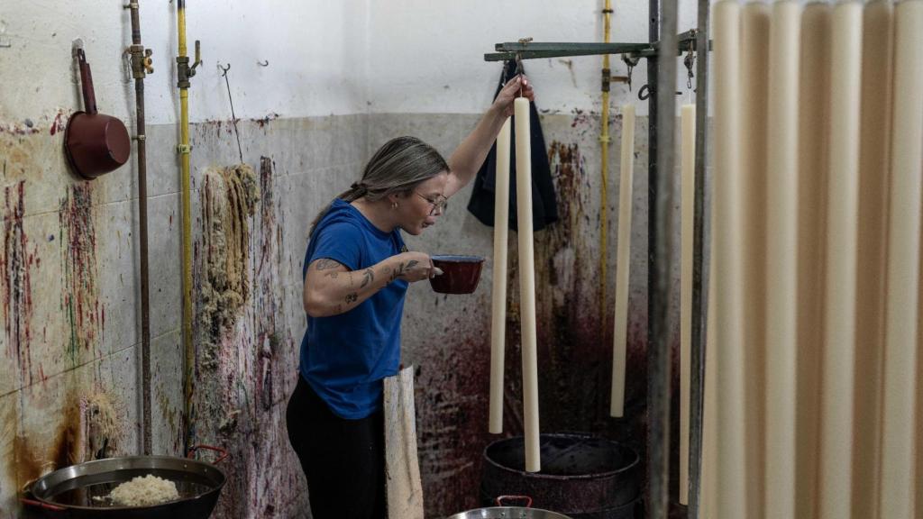Una mujer da color a las velas elaboradas por Cera Bellido.