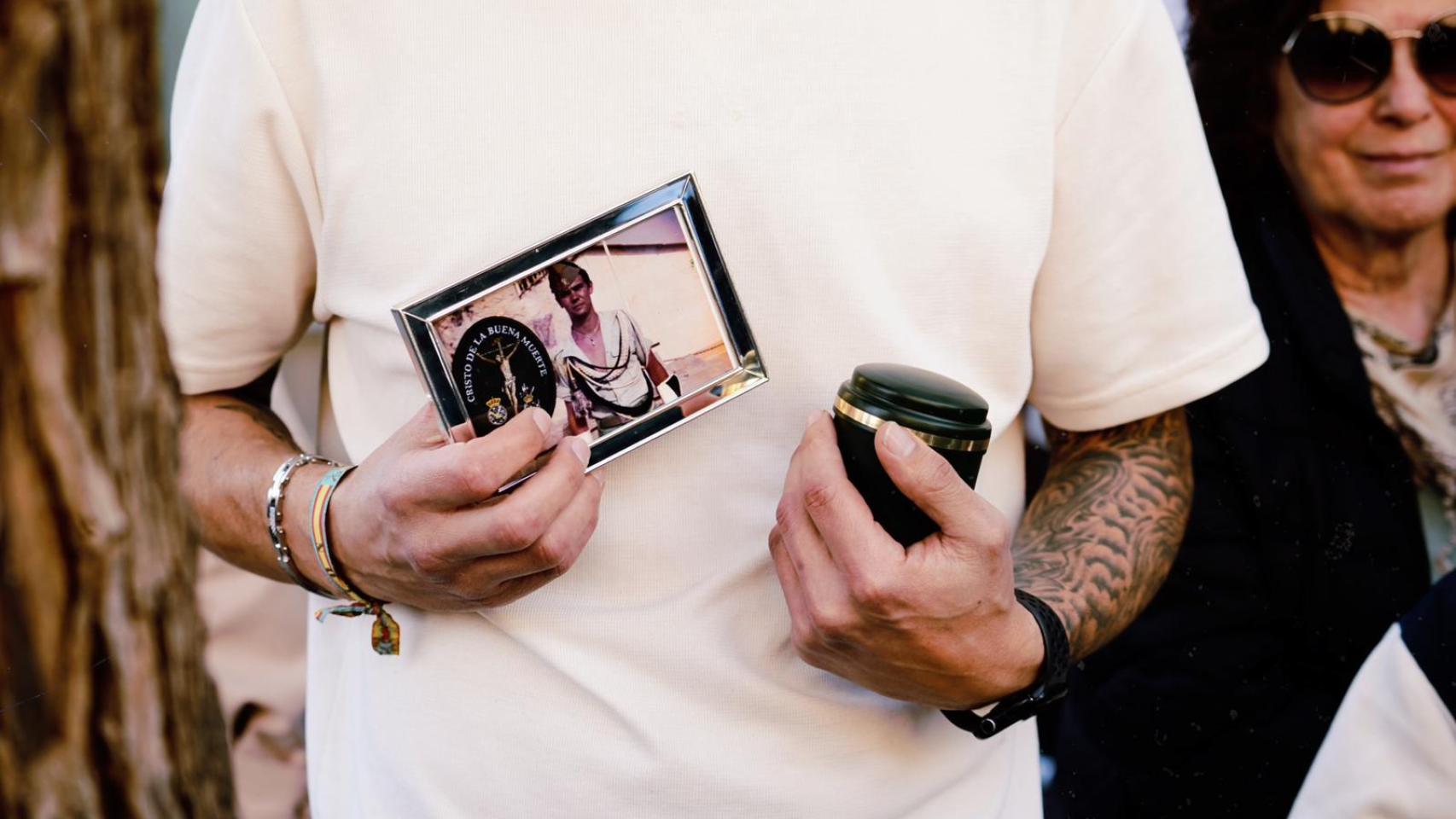 Sergio sostiene las cenizas y la foto de su padre.