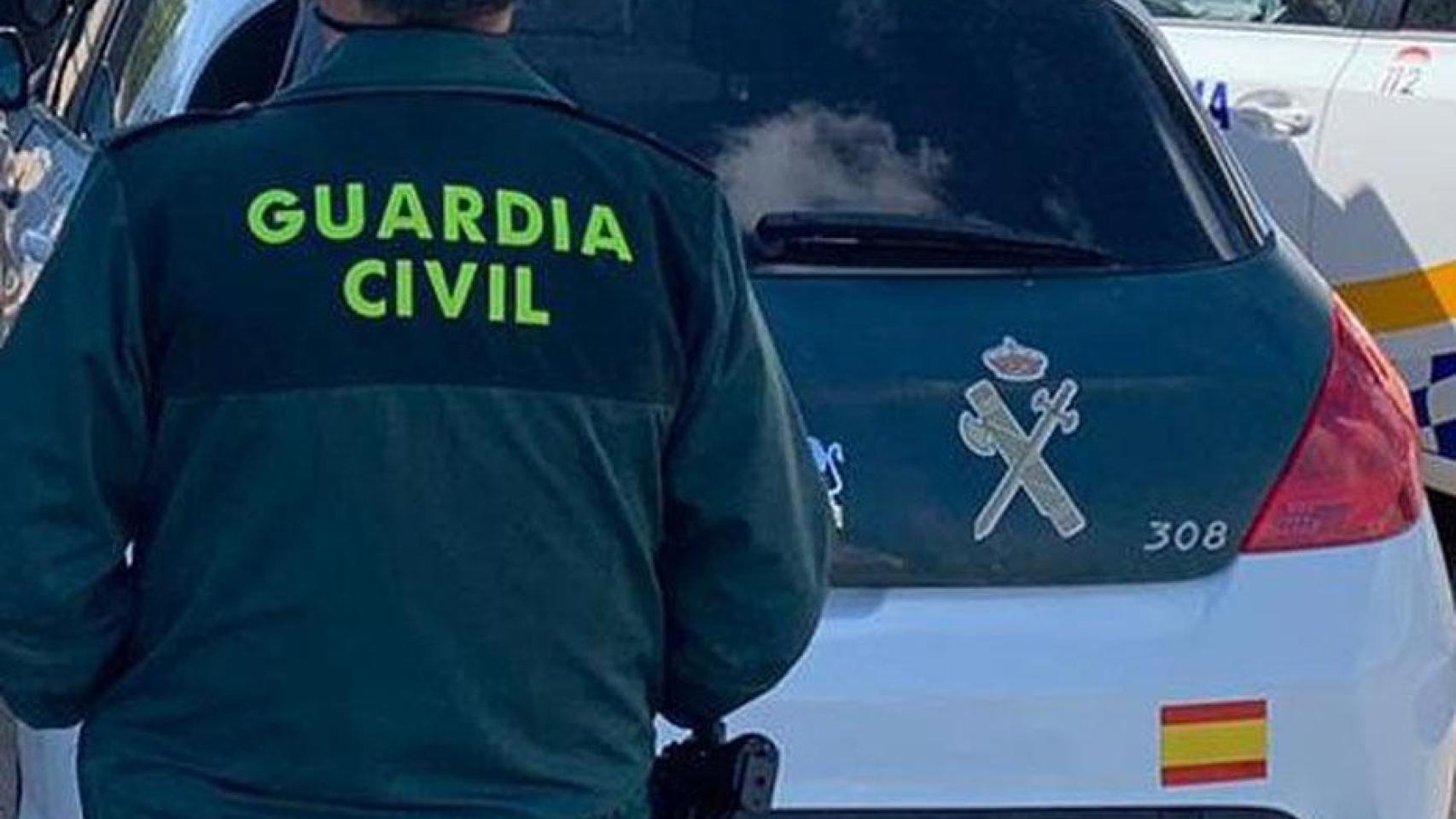 Agente de la Guardia Civil junto a un vehículo oficial.