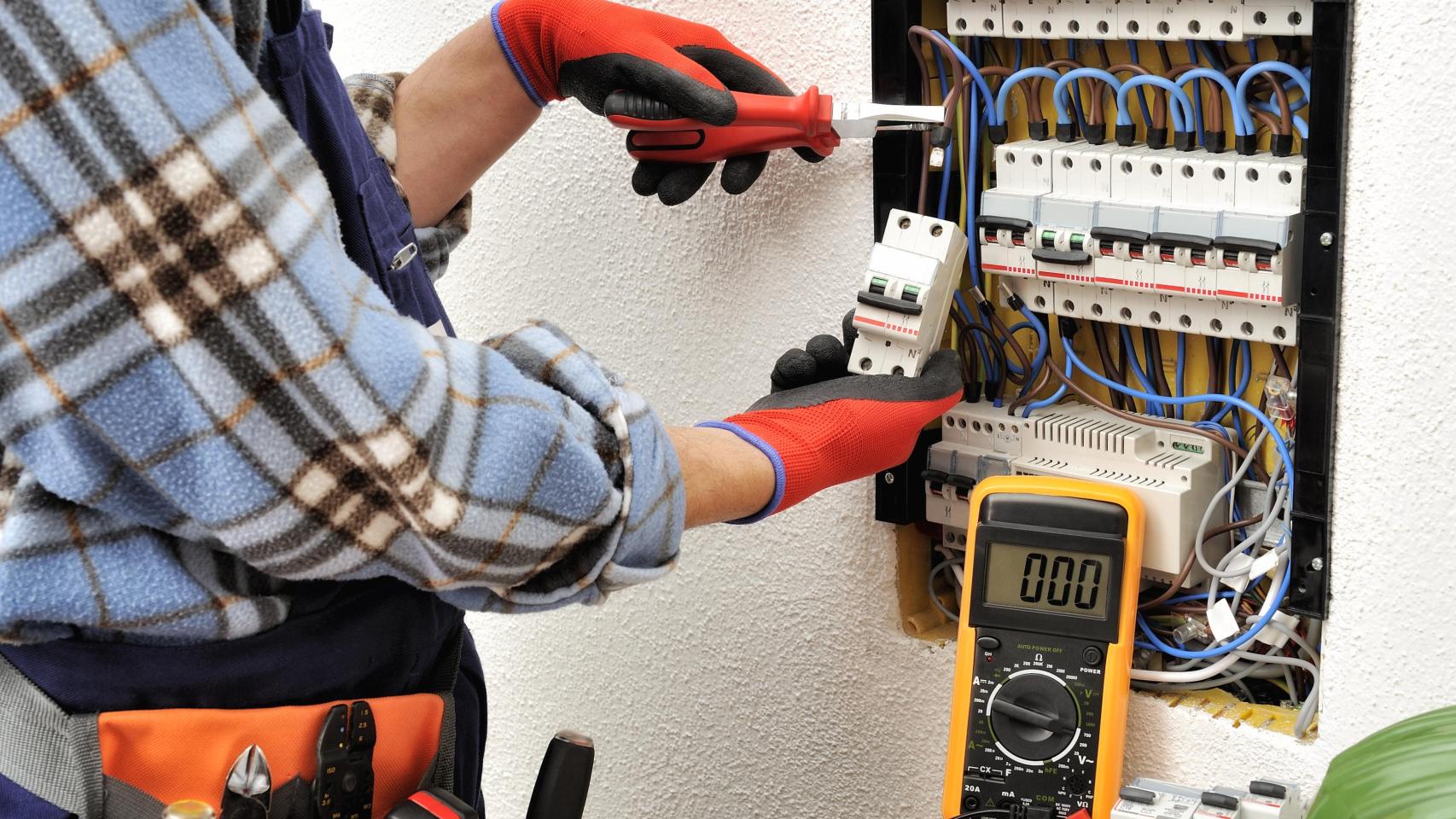 Un electricista trabajando en un cuadro eléctrico.